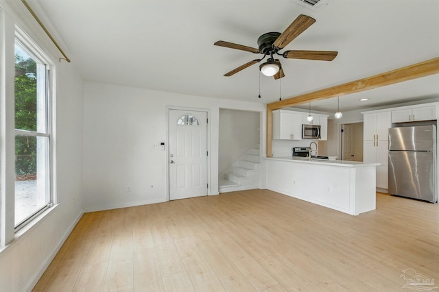 unfurnished living room with a sink, baseboards, a ceiling fan, and light wood-type flooring