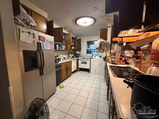 kitchen featuring light tile patterned flooring, white appliances, a textured ceiling, and washer and dryer