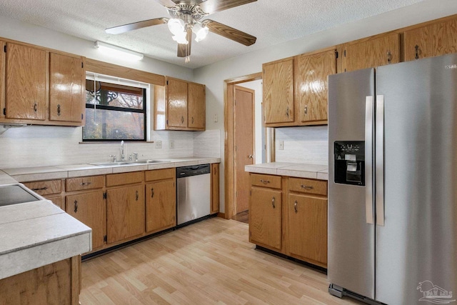 kitchen featuring sink, ceiling fan, stainless steel appliances, decorative backsplash, and light wood-type flooring