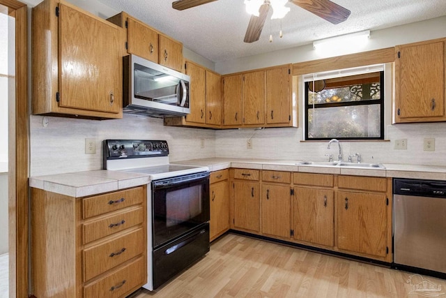 kitchen featuring stainless steel appliances, light hardwood / wood-style floors, sink, and a textured ceiling