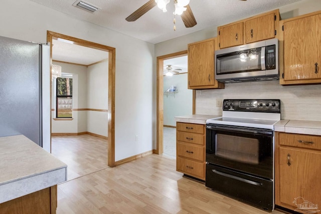 kitchen featuring stainless steel appliances, a textured ceiling, light wood-type flooring, and decorative backsplash