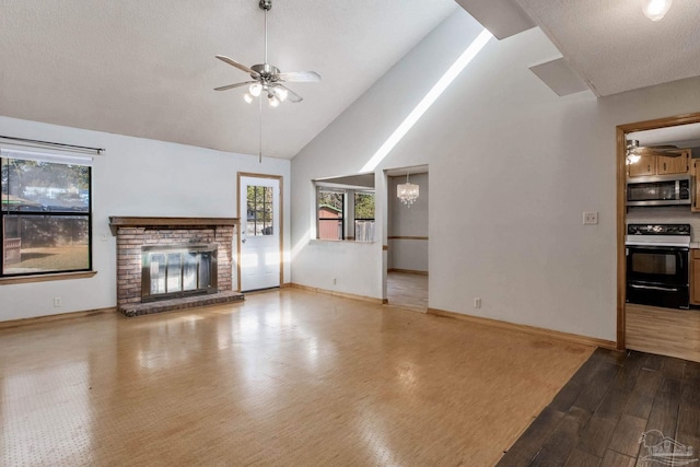 unfurnished living room featuring high vaulted ceiling, a textured ceiling, a brick fireplace, ceiling fan with notable chandelier, and light wood-type flooring