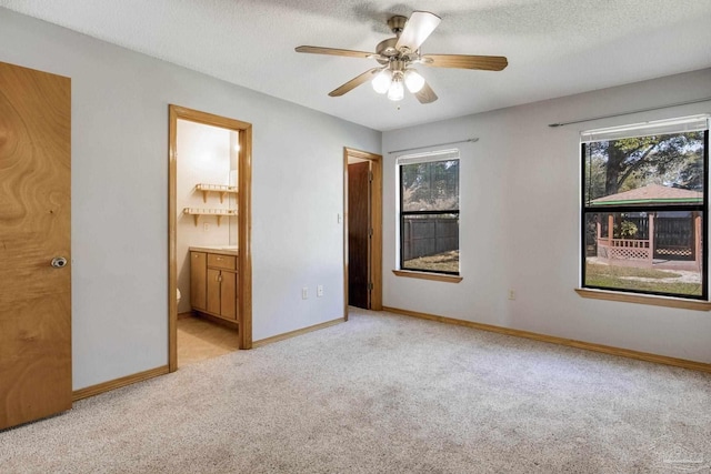 unfurnished bedroom featuring multiple windows, connected bathroom, light colored carpet, and ceiling fan