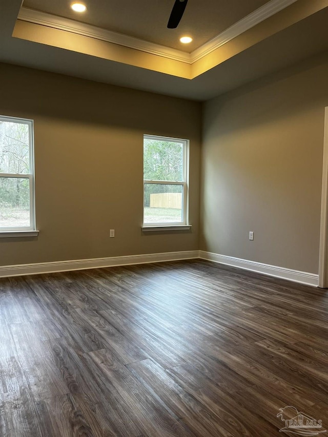 empty room with dark wood-style floors, baseboards, recessed lighting, ornamental molding, and a raised ceiling