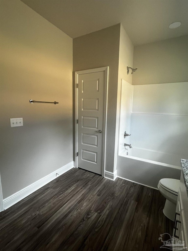 bathroom featuring bathtub / shower combination, toilet, wood finished floors, and baseboards