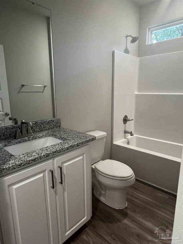 bathroom with vanity, toilet, wood finished floors, and tub / shower combination