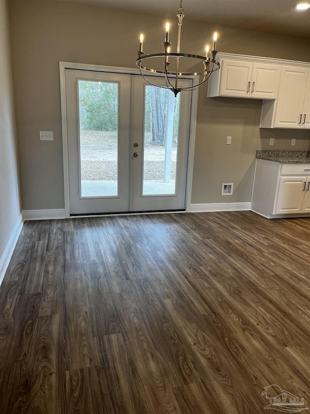 unfurnished dining area with visible vents, baseboards, dark wood finished floors, french doors, and a notable chandelier