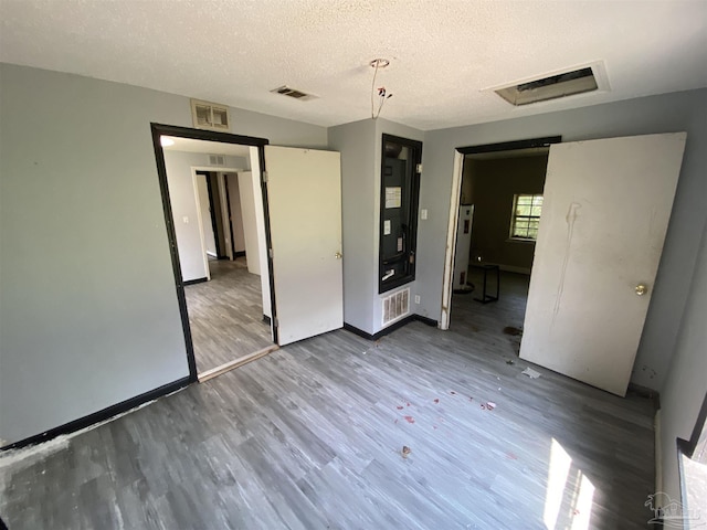 unfurnished bedroom featuring heating unit and hardwood / wood-style floors