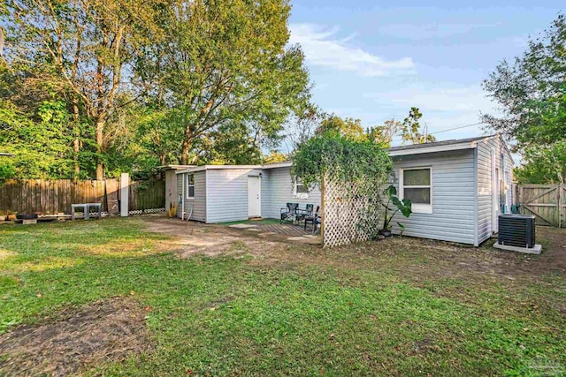 back of property with central AC unit, a patio area, and a lawn