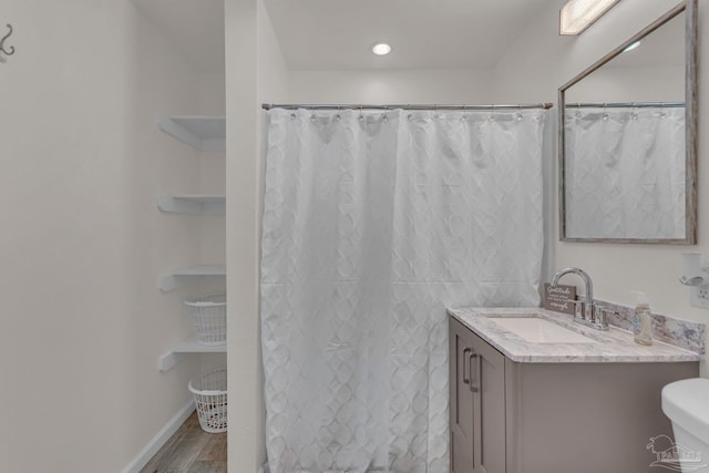 bathroom with hardwood / wood-style floors, vanity, toilet, and walk in shower