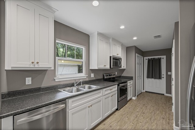6609 Cedar St, Milton, FL 32570 - kitchen with stainless steel appliances, dark countertops, white cabinetry, light wood-style floors, and recessed lighting