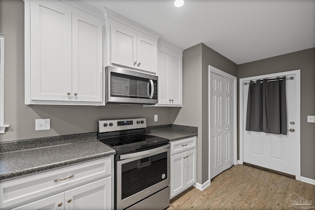 6609 Cedar St, Milton, FL 32570 - kitchen featuring appliances with stainless steel finishes, dark countertops, light wood-type flooring, and white cabinetry