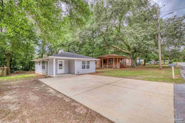 6609 Cedar St, Milton, FL 32570 - bungalow with covered porch, driveway, view of wooded area, and a front yard