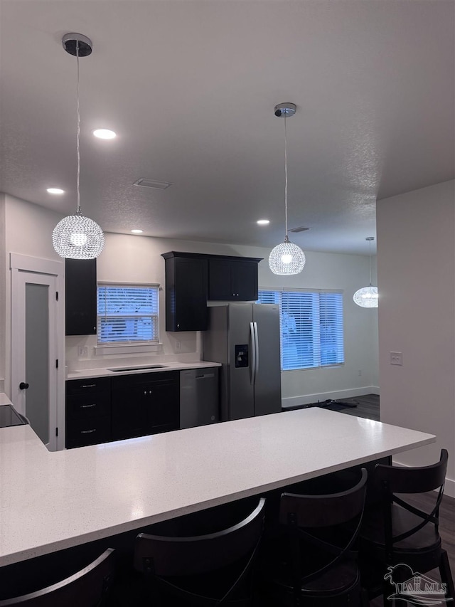 kitchen with dark hardwood / wood-style flooring, a kitchen bar, decorative light fixtures, and appliances with stainless steel finishes