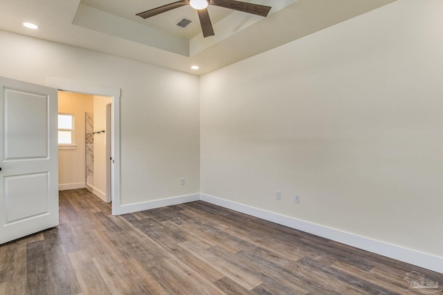 spare room featuring a tray ceiling, wood-type flooring, and ceiling fan