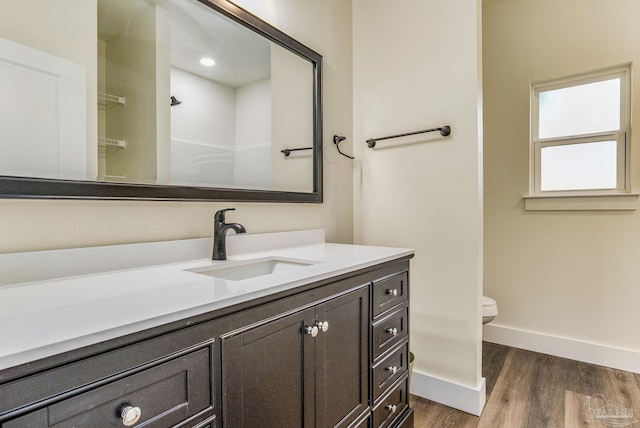 bathroom with wood-type flooring, walk in shower, vanity, and toilet