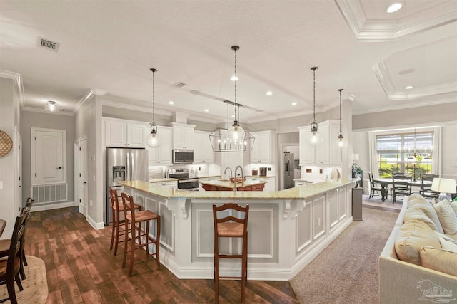 kitchen with a spacious island, decorative light fixtures, appliances with stainless steel finishes, and a kitchen breakfast bar