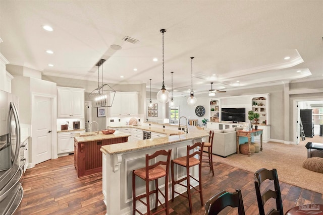 kitchen with ceiling fan with notable chandelier, a breakfast bar area, dark wood-type flooring, decorative light fixtures, and a large island with sink