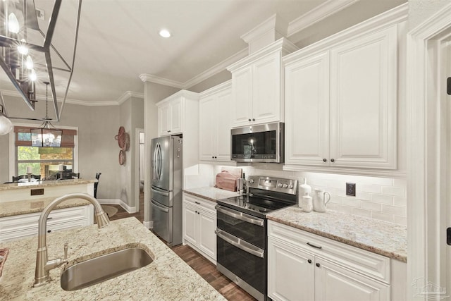 kitchen with pendant lighting, appliances with stainless steel finishes, white cabinets, and light stone countertops