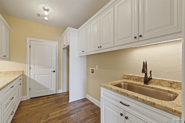 washroom with cabinets, separate washer and dryer, sink, dark hardwood / wood-style floors, and a textured ceiling