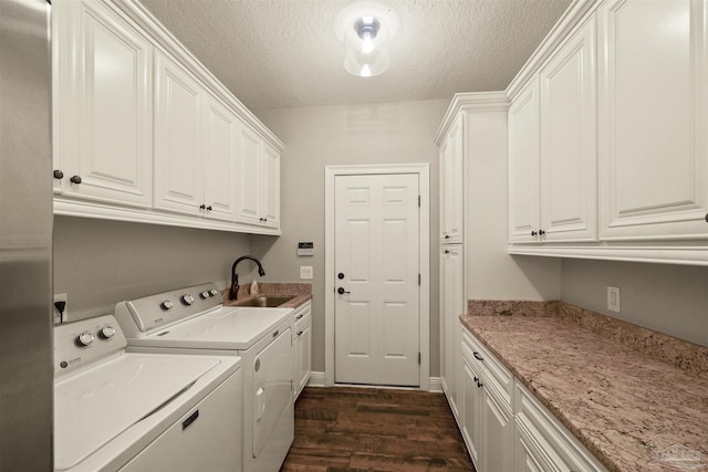 washroom featuring separate washer and dryer, sink, dark hardwood / wood-style flooring, cabinets, and a textured ceiling