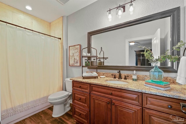 bathroom with ceiling fan, hardwood / wood-style floors, vanity, walk in shower, and toilet