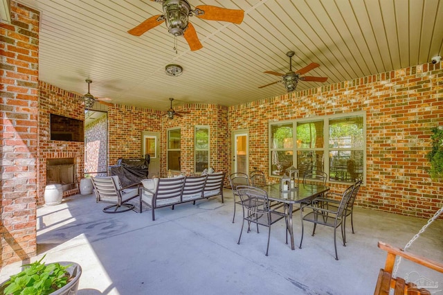 view of patio featuring an outdoor brick fireplace and ceiling fan