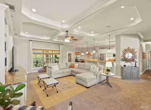 living room with ceiling fan with notable chandelier, light carpet, crown molding, and coffered ceiling