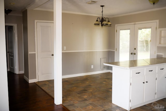 kitchen with french doors, pendant lighting, tile countertops, an inviting chandelier, and white cabinets