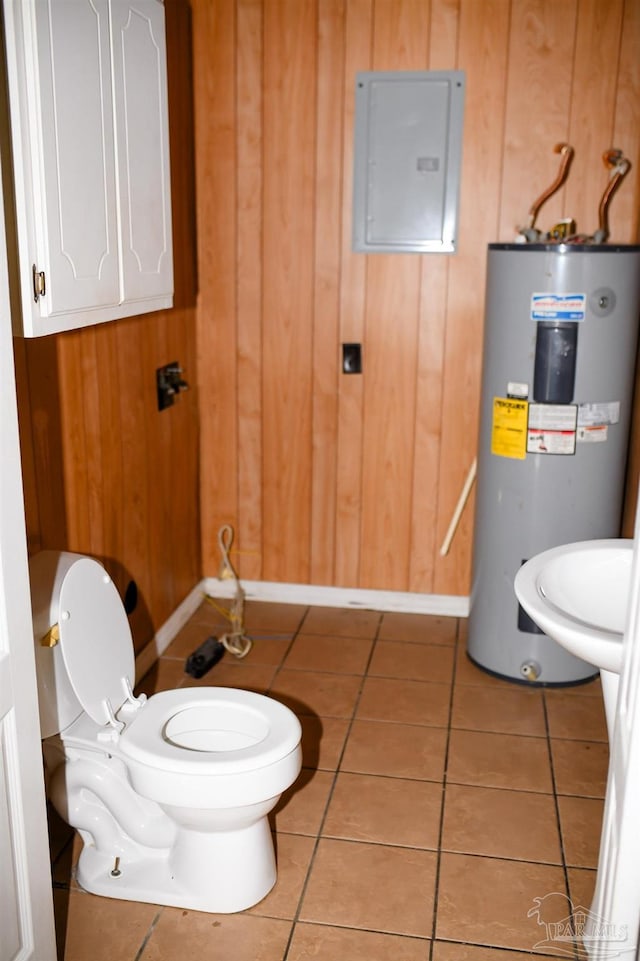 bathroom featuring tile patterned floors, electric water heater, electric panel, toilet, and wood walls