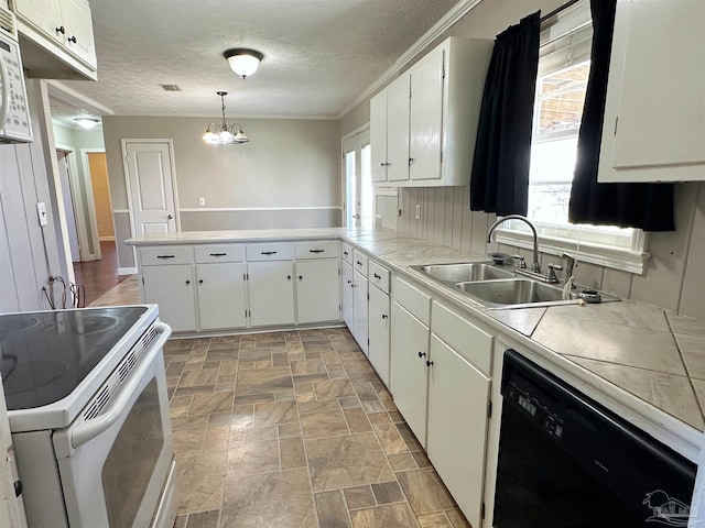 kitchen with hanging light fixtures, white cabinets, a sink, white appliances, and a peninsula