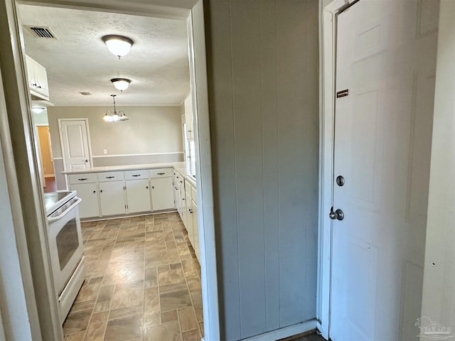 kitchen featuring light countertops, white electric range, hanging light fixtures, visible vents, and white cabinets