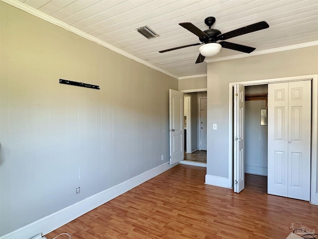 unfurnished bedroom with crown molding, a closet, visible vents, wood finished floors, and baseboards