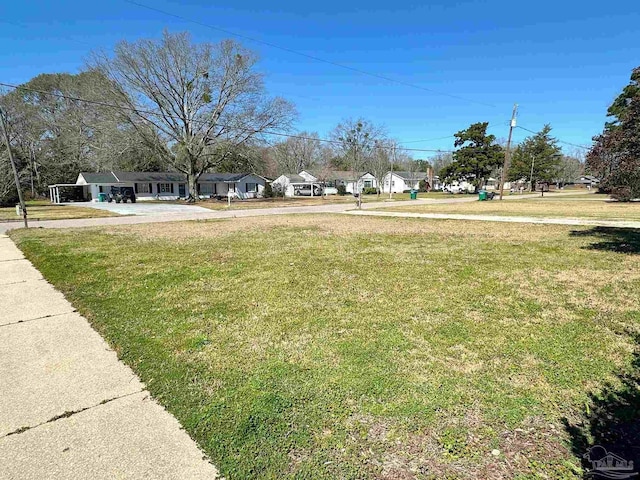 view of yard featuring a residential view and concrete driveway