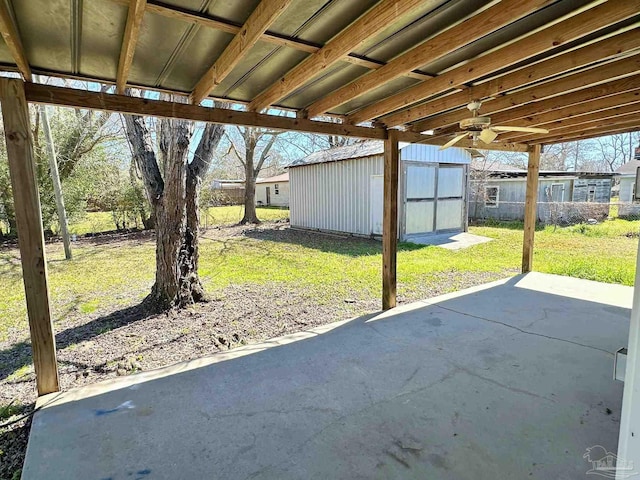 view of patio with an outbuilding, ceiling fan, a storage shed, and fence