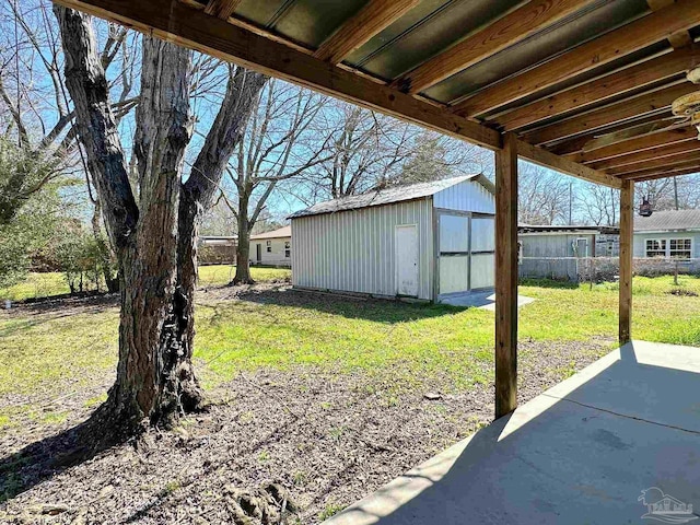 view of yard featuring a storage shed, a patio, an outdoor structure, and fence