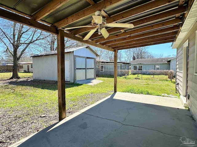 view of patio featuring a storage unit, an outdoor structure, fence, and a ceiling fan