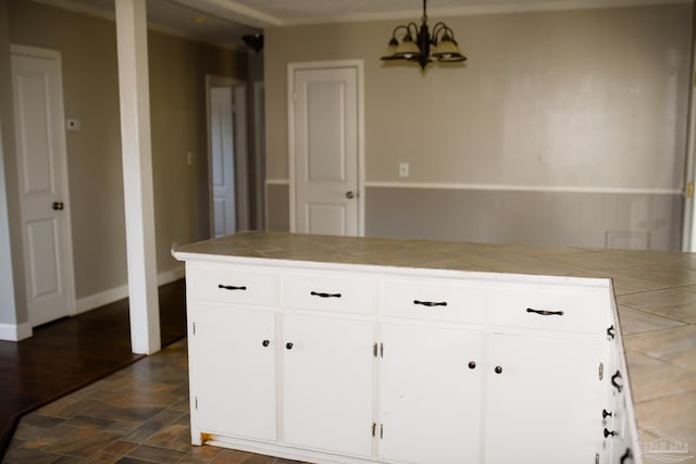 kitchen with pendant lighting, a notable chandelier, white cabinets, and tile countertops