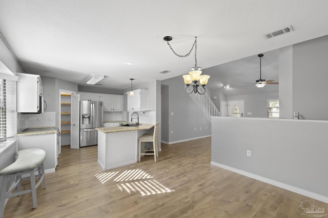 kitchen with stainless steel fridge with ice dispenser, white cabinetry, tasteful backsplash, hanging light fixtures, and sink