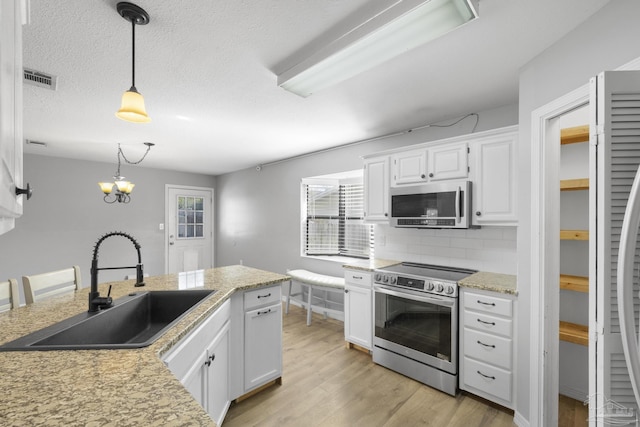 kitchen featuring pendant lighting, sink, white cabinetry, and appliances with stainless steel finishes