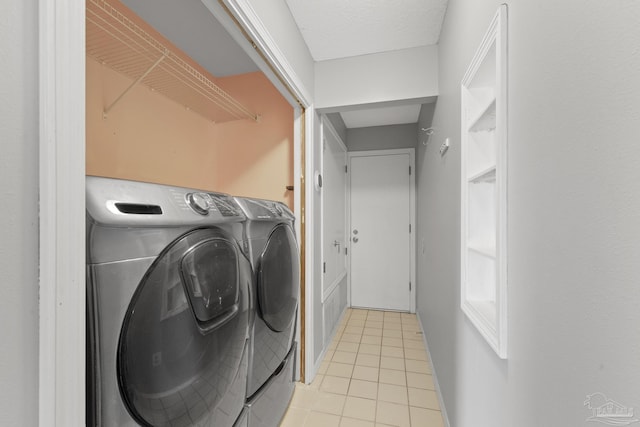 clothes washing area featuring washer and dryer, a textured ceiling, and light tile patterned flooring