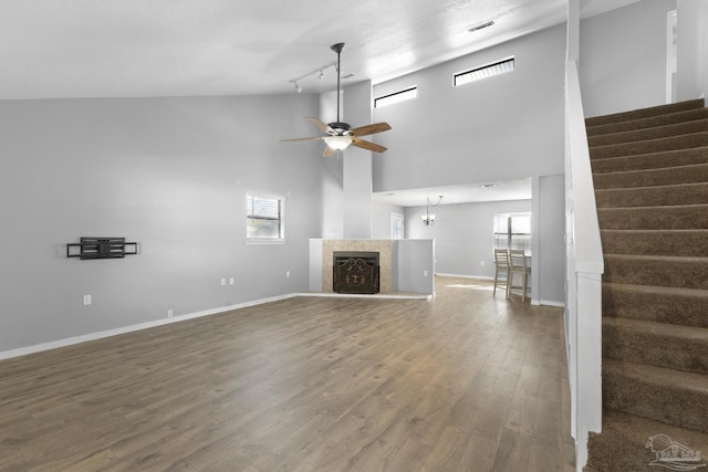 unfurnished living room featuring high vaulted ceiling, hardwood / wood-style flooring, track lighting, and ceiling fan