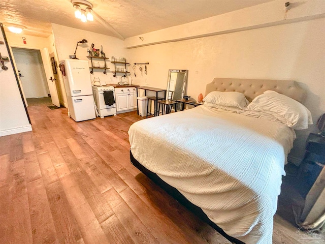 bedroom with white refrigerator, light hardwood / wood-style floors, a textured ceiling, and sink