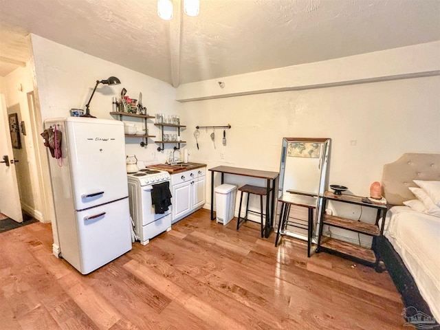 kitchen with white cabinets, light hardwood / wood-style flooring, sink, and white appliances