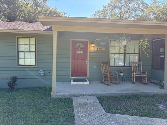 view of exterior entry featuring a porch and a yard