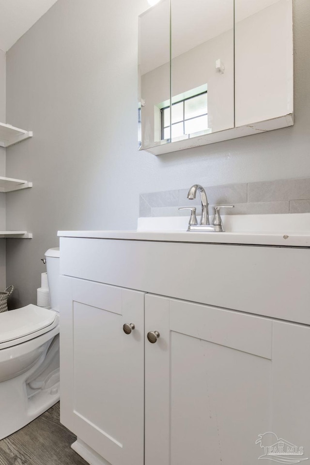 bathroom featuring wood-type flooring, vanity, and toilet