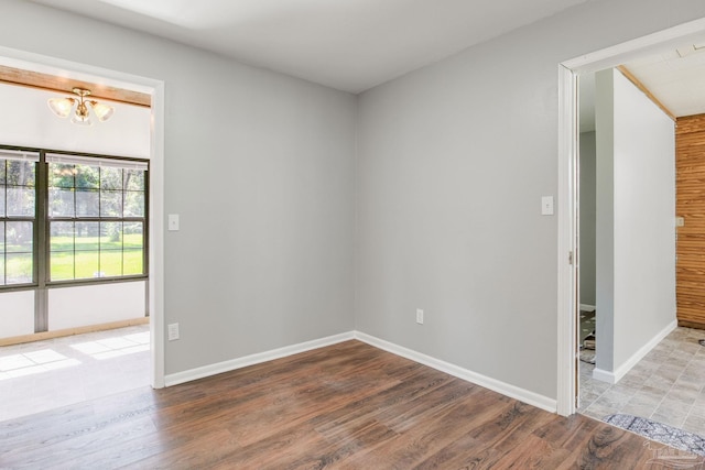 unfurnished room with hardwood / wood-style flooring and a notable chandelier