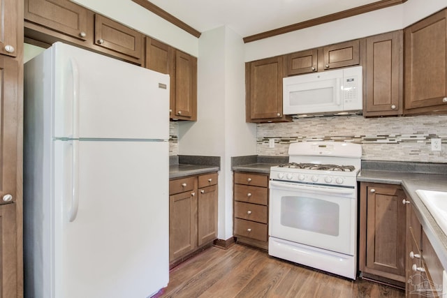 kitchen featuring crown molding, dark wood-type flooring, white appliances, and decorative backsplash