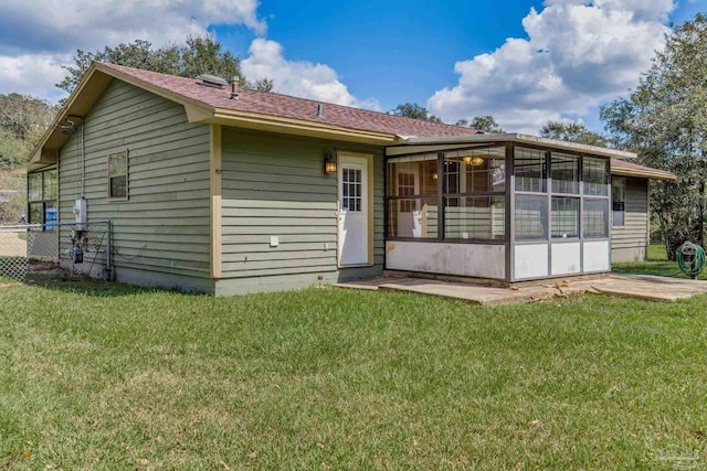 rear view of house featuring a sunroom and a lawn