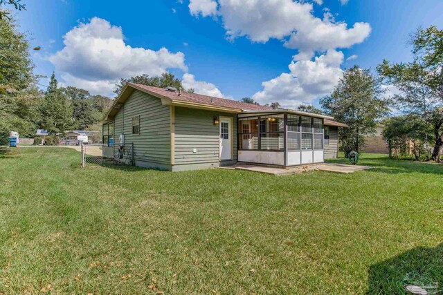 rear view of property with a lawn and a sunroom